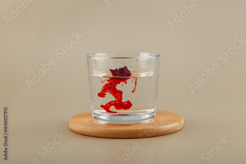 Powder of Allura Red AC or FD&C Red 40 dissolves in water, turning it red. Glass cup with red azo dye. Food additive E129 provides high solubility and stable coloring of products