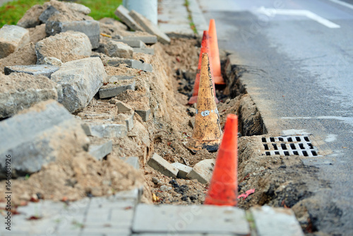 Photos Road repair work with curb replacement and installation in progress, traffic cones and pylons for safety during city infrastructure improvement and maintenance
