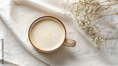 Overhead view of a creamy latte in a rustic mug with dried flowers