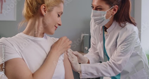 Wallpaper Mural Female doctor in protective mask giving injection to adult woman patient in clinic. Friendly nurse administering vaccine into upper arm. Immunization, preventive treatment and health care concept. Torontodigital.ca