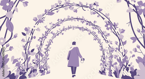 Woman with camera walks through tunnel of flowering branches in springtime season