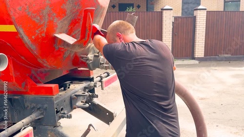 Worker holds a pipe and pumps out a domestic septic tank. Sewer and Drain Cleaning Services
