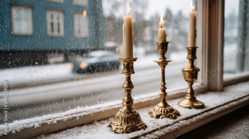 Three golden candlesticks with burning candles on winter window  
