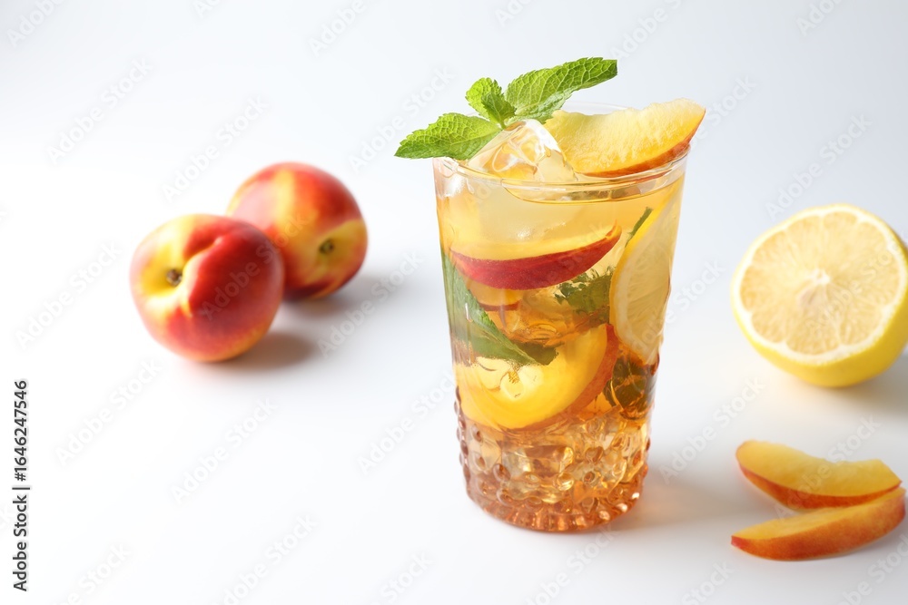 Fototapeta premium Tasty iced tea with lemon, peaches and mint on white background