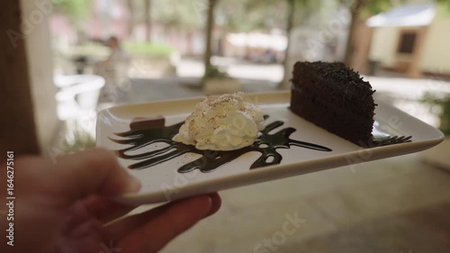 Slice of chocolate cake with whipped cream and chocolate syrup on a white plate