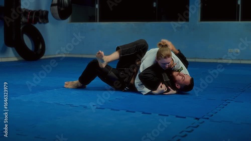 Man and woman training Brazilian Jiu-Jitsu grappling on mat