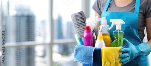 Cleaner holds cleaning supplies bucket near city view window