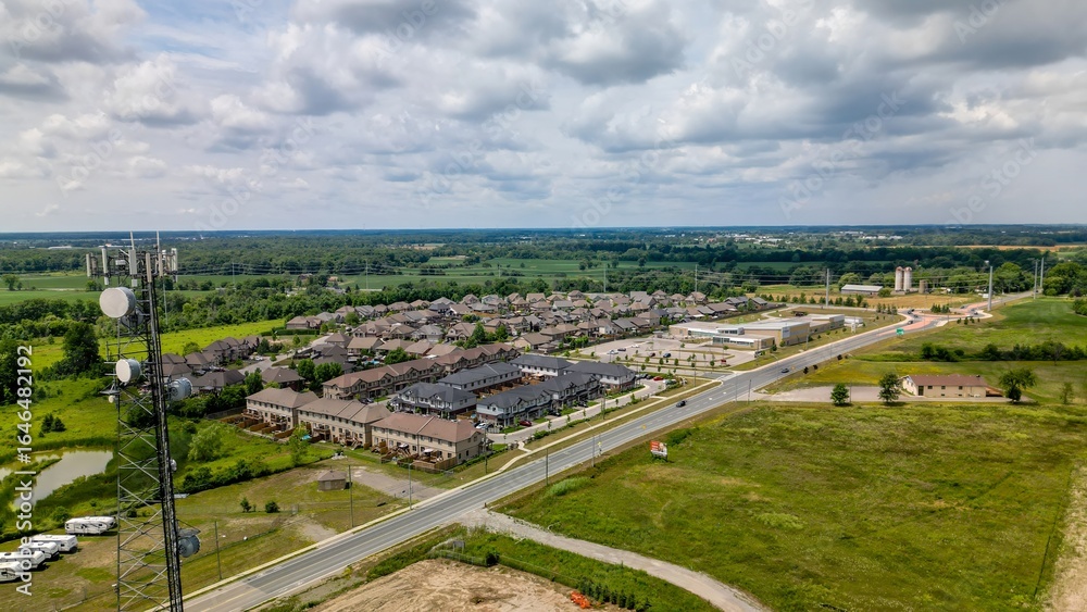 Drone view of cell tower next to suburban housing and green fields Drone view of cell tower next to suburban housing and green fields