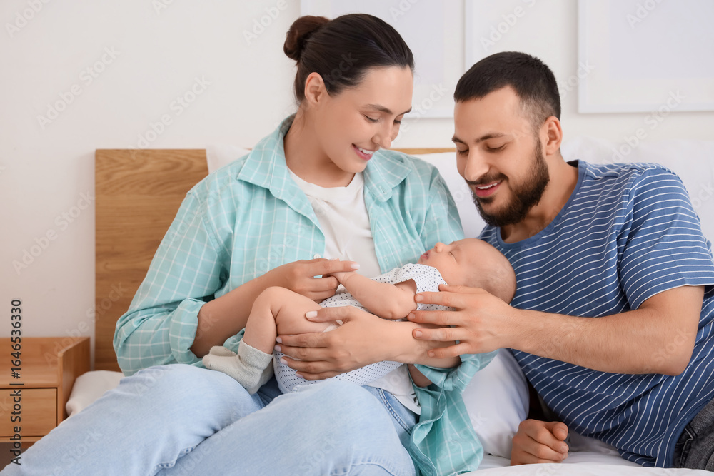 Obraz premium Happy parents with their little baby sitting in bedroom