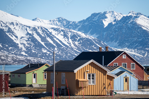 Colorful buildings at the base of snow covered mountans in the research base at Ny Alesund, Svalbard, Norway