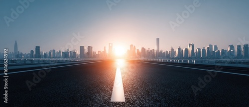 Fototapeta Naklejka Na Ścianę i Meble -  Empty road leading to city skyline at sunrise