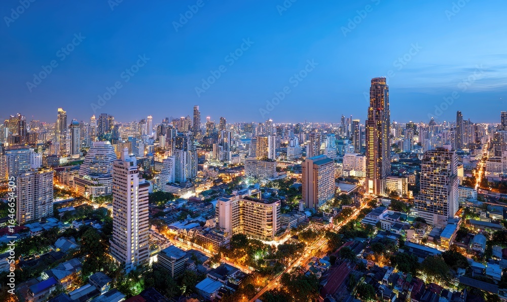 Fototapeta premium Panoramic city skyline at twilight. Dense urban sprawl of high-rises and streets. Soft, illuminated buildings against a clear blue-toned sky