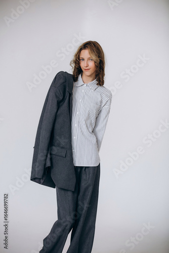 A teenage girl model is young and beautiful in a business suit and shirt in a studio on a white background