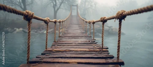 Panel kuchenny z motywem A weathered wooden suspension bridge stretches across a misty river, disappearing into the fog