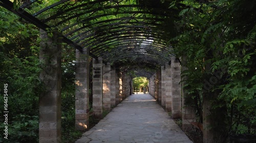 Wallpaper Mural Stone pathway under green archway in Athens National Garden with benches and columns, no people, sunlight and shade, peaceful tourist spot in Greece Torontodigital.ca