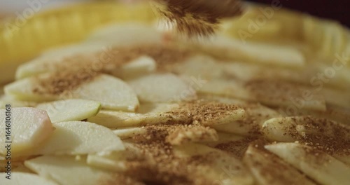 Close up of sliced apples being sprinkled with brown sand and cinnamon while making delicious sweet pie in cozy kitchen. Baking and Fruit filling