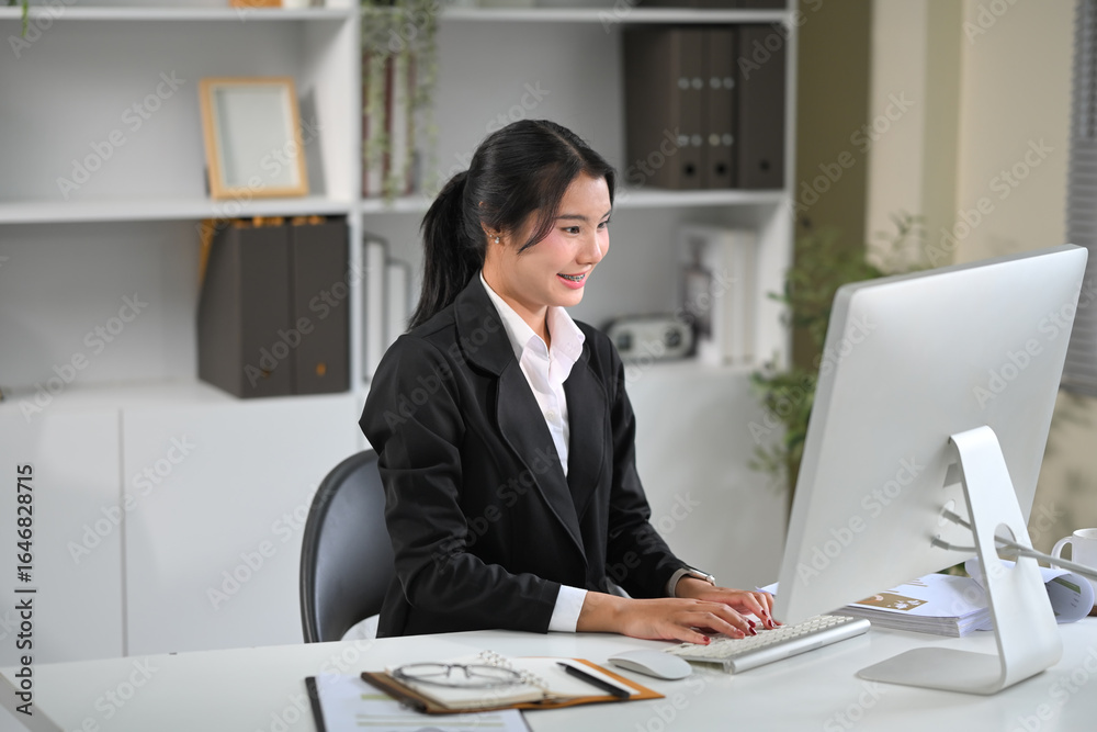 Confident young businesswoman working on a desktop computer in a modern office Confident young businesswoman working on a desktop computer in a modern office
