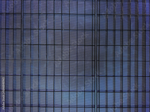 Close up of building glass window pattern with black metal frames in blue color. Blue tinted glass color as curtain wall. Seamless background texture.