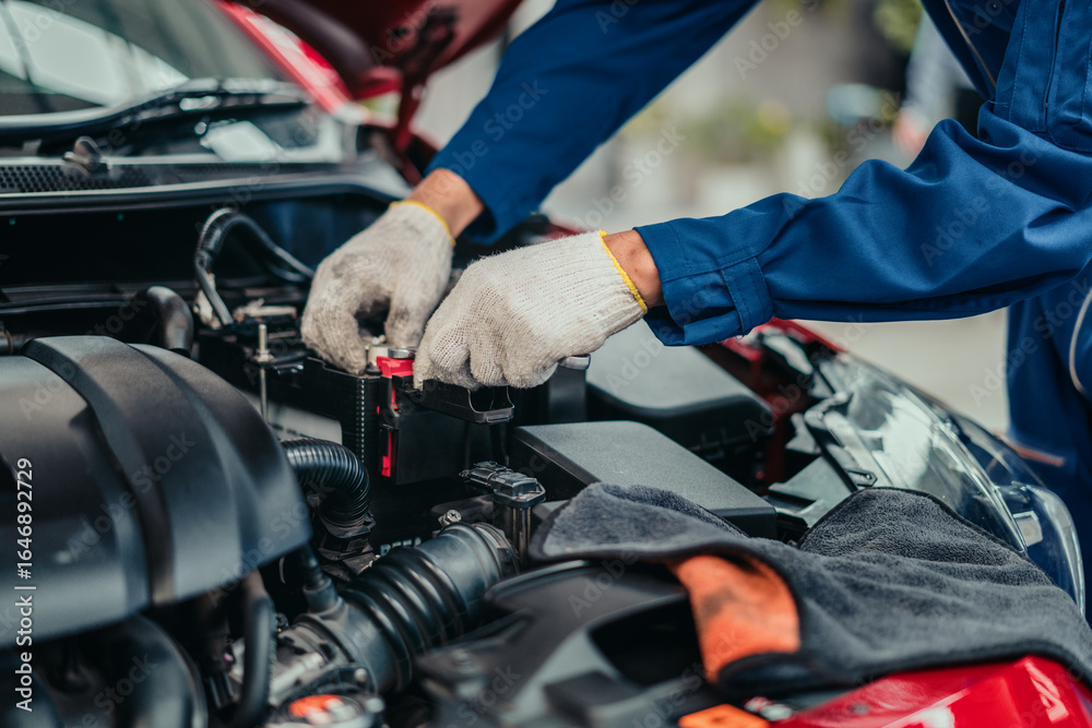 Obraz premium Mechanic inspecting and tightening battery terminal in workshop, representing professional service, quality check, and safety in automotive maintenance industry.