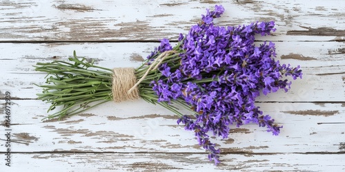 A vibrant bunch of lavender flowers tied with twine, resting on a rustic wooden surface, showcasing their rich purple hue.