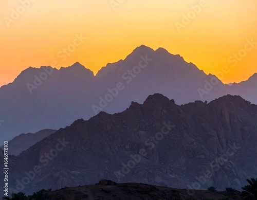 Sunset silhouettes of layered mountains with warm hues