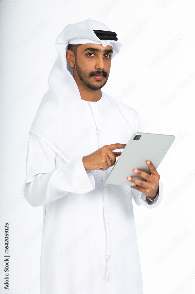 Portrait of an emirati man on a white background using an ipad. Portrait of an emirati man on a white background using an ipad.