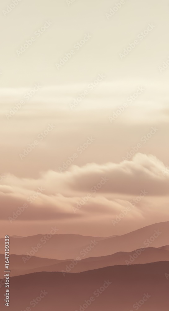 Obraz premium Layered mountain ranges fade into soft clouds under a pale sky, creating a serene and tranquil natural landscape at dawn