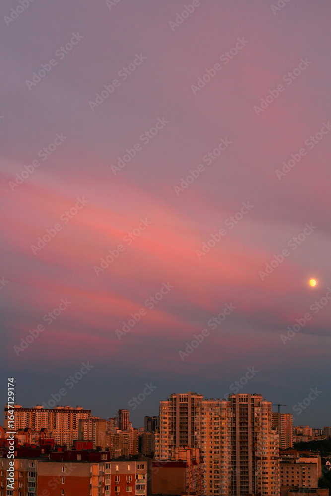 Fototapeta premium Bright sky at sunset, clouds, warm colors almost red, moon and houses