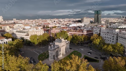 Aerial view of the Puerta de Alcalá, a neoclassical monument amidst autumnal trees and bustling traffic in Madrid, Comunidad de Madrid, Spain.