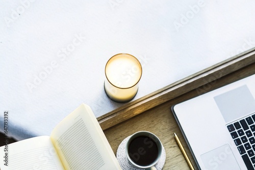 Cozy Work Corner: Overhead view of a warm-toned desk with a candle, book, coffee cup, and laptop