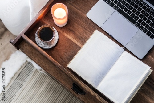 Cozy Work Corner: Overhead view of a warm-toned desk with a candle, book, coffee cup, and laptop