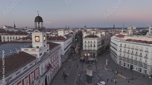 Aerial view of the clock tower at Puerta del Sol amidst the city's skyline, showcasing building rooftops and street activity, Madrid, Puerta del Sol, Spain.