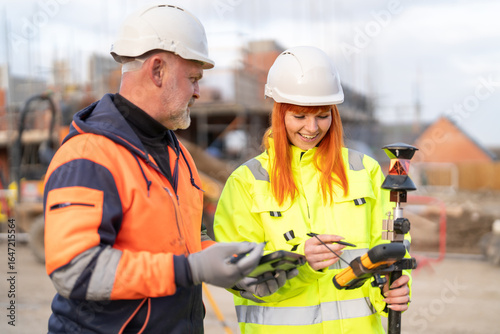Photos Construction engineers surveyors collaborating on site, using modern theodolite