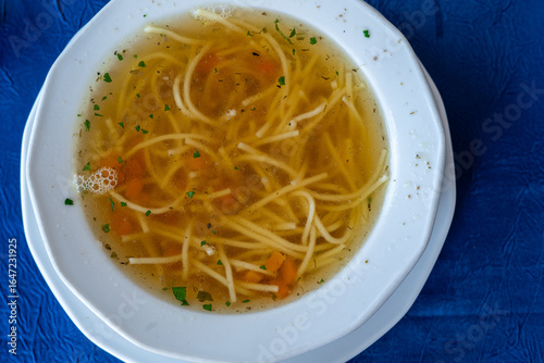 Traditional Polish noodle soup (rosół) with carrots and herbs