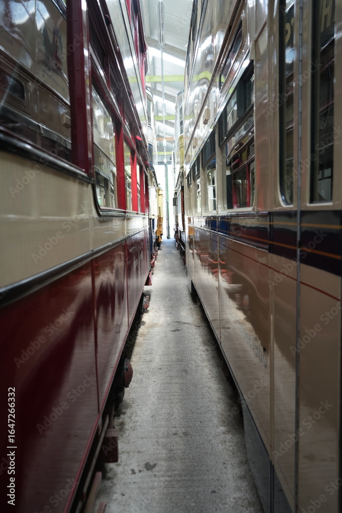 Obraz premium Crich Tramway Museum, England – August 13 2025: Close Up View Between Vintage Edwardian Double Deck Trams in the Depot
