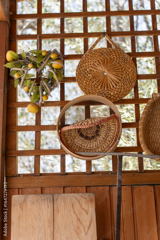 Obraz premium Woven baskets and citrus hanging in sunlit wooden shelter, showcasing traditional craftsmanship and rustic charm