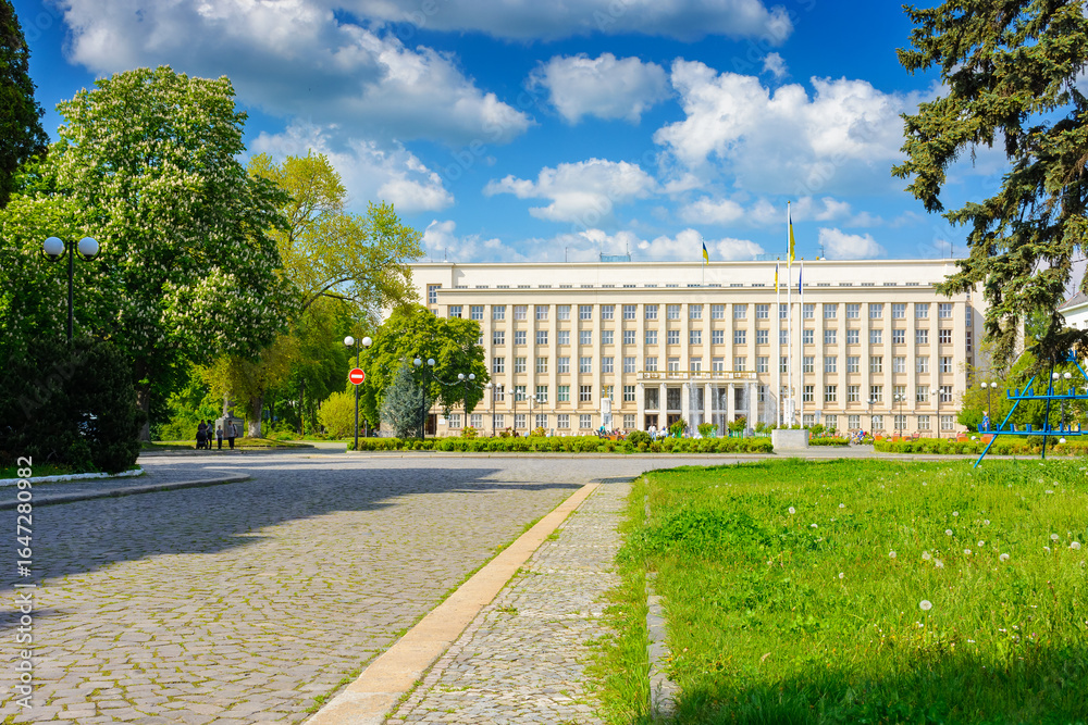 Fototapeta premium uzhhorod, ukraine - 06 may, 2017: government building of zakarpattia state administration. czechoslovakia architecture and cobblestone street of transcarpathia capital in evening light. narodna square