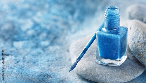 Flacone di smalto blu scintillante su pietre, con sfondo sfocato blu e bianco.