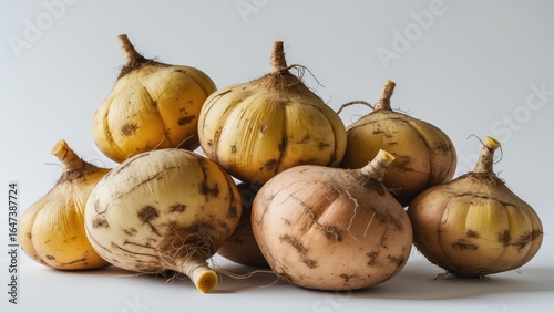 A group of onions with papery skin and roots, isolated on a light background.