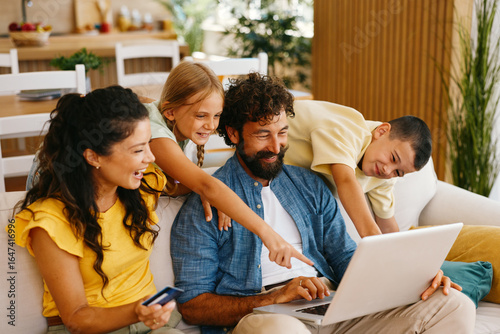 Happy family doing online shopping using laptop and credit card at home
