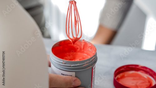 Foto A close-up shot of pink paint being stirred and prepared with a mixing brush in