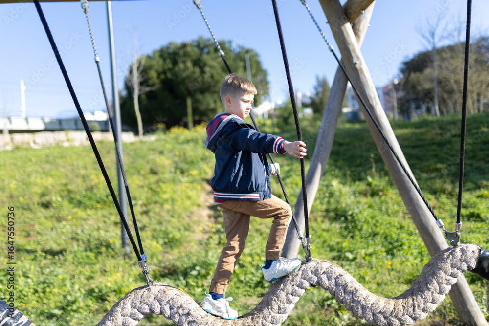 Young boy balancing on a swinging beam at the playground Young boy balancing on a swinging beam at the playground