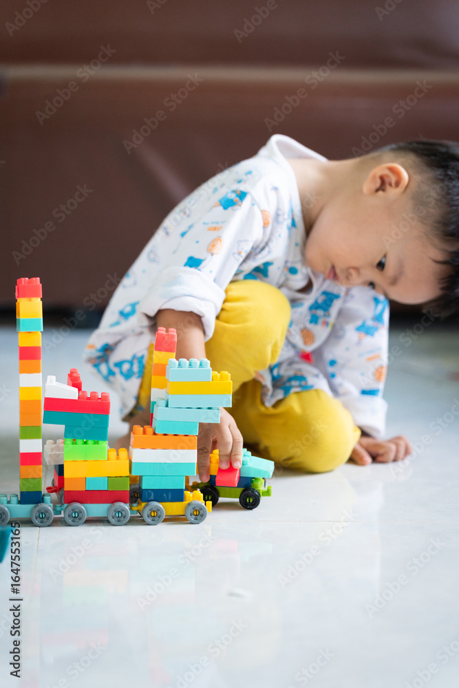 Fototapeta premium Child Playing with Colorful Building Blocks Indoors