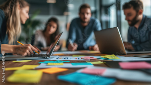 a creative marketing team brainstorming around a table with sticky notes and laptops