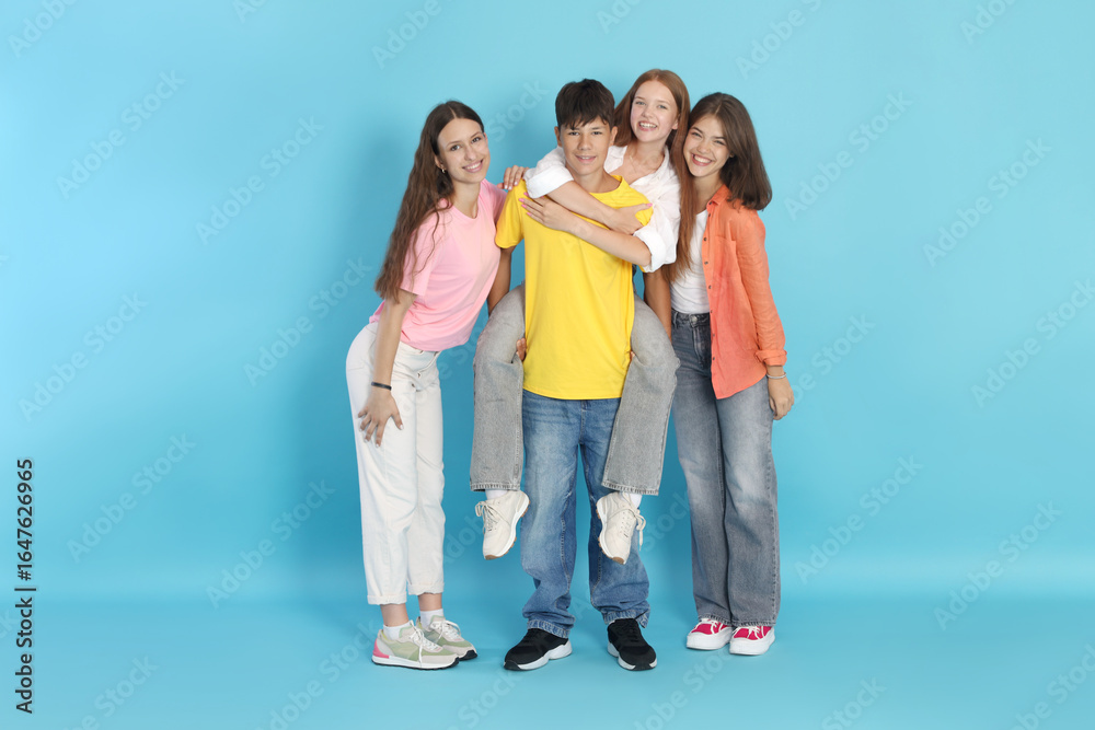 Obraz premium Full-length portrait of happy teenage friends on light blue background