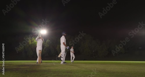 Diverse male team bowling at night batsman missing drive keeper breaking wicket for stumping