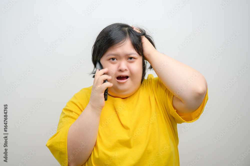 Portrait of an Asian woman with Down syndrome, talking on mobile phone with a surprised and concerned expression, one hand on head, Down syndrome awareness, on a clean white background. Portrait of an Asian woman with Down syndrome, talking on mobile phone with a surprised and concerned expression, one hand on head, Down syndrome awareness, on a clean white background.