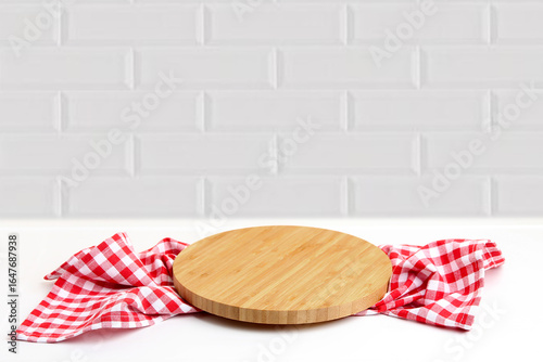 Round cutting board with checkered kitchen towel on white table