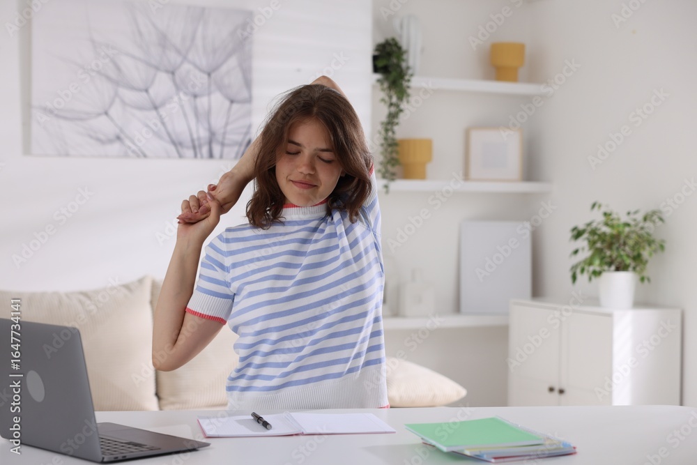 Obraz premium Beautiful teenage girl stretching at table indoors, space for text