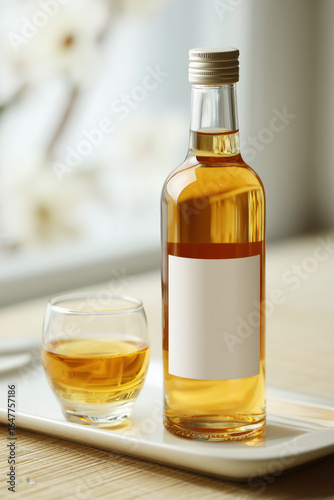 bottle of japanese plum wine with elegant minimal label, placed on a clean white ceramic tray, next to a small glass filled with golden liquid